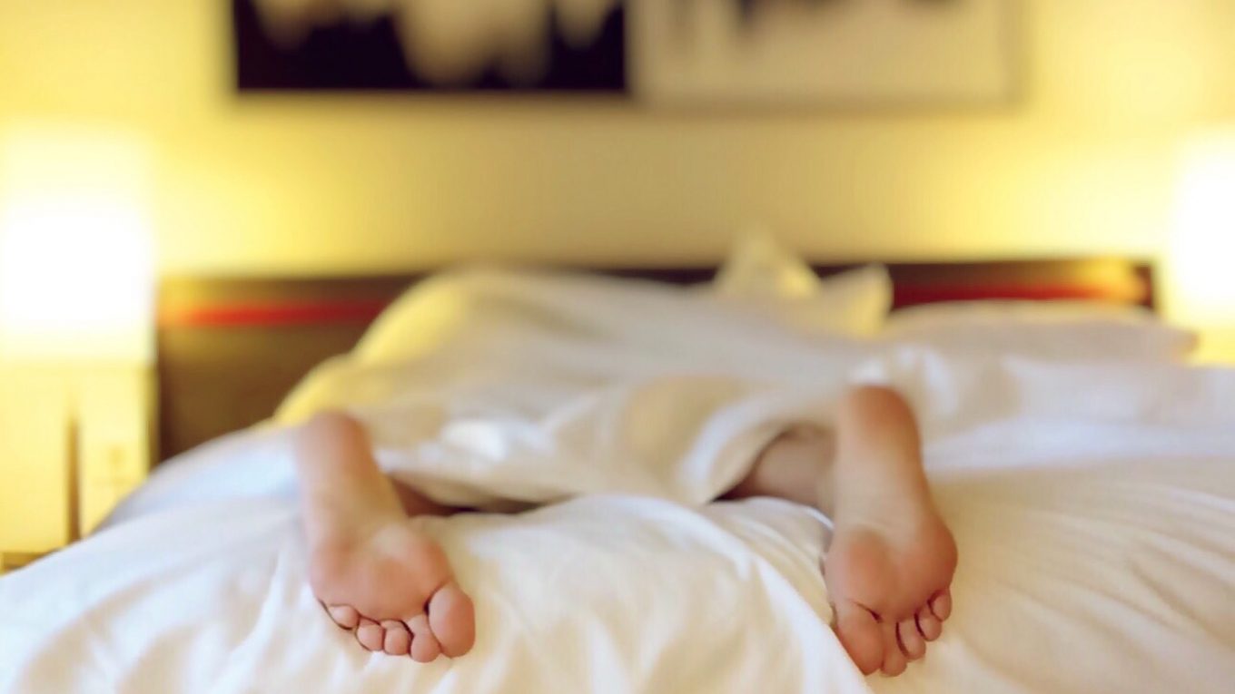 out of focus image of persons feet in bed