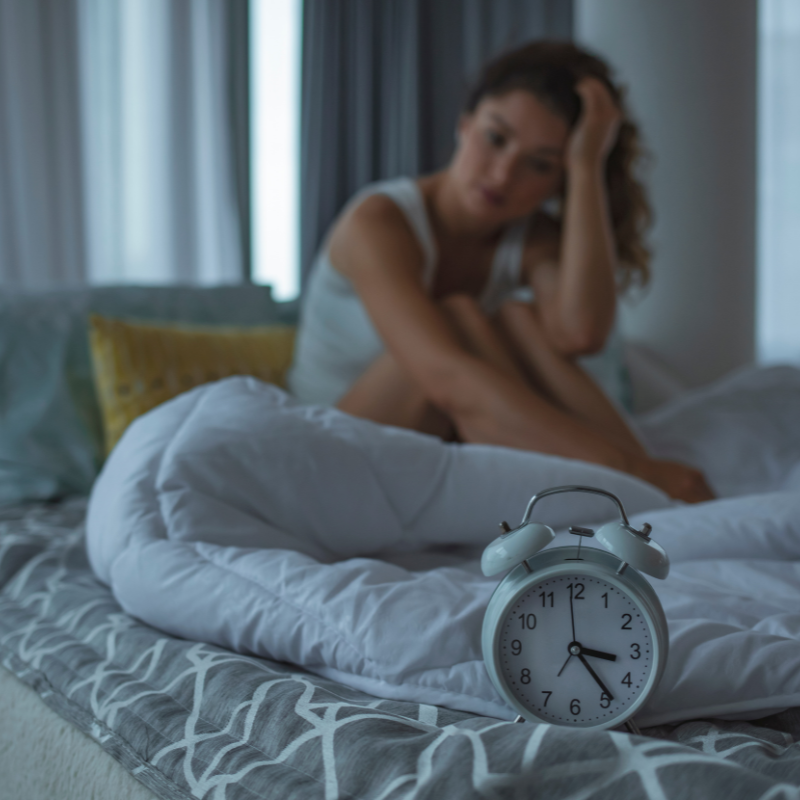 Woman with insomnia looking at alarm clock
