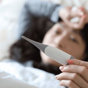 Women lying in bed looking at a thermometer 