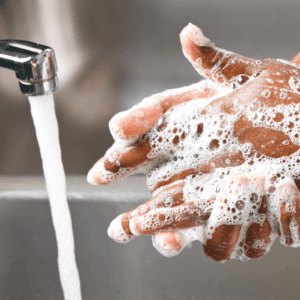 Person washing their hands next to a running tap 